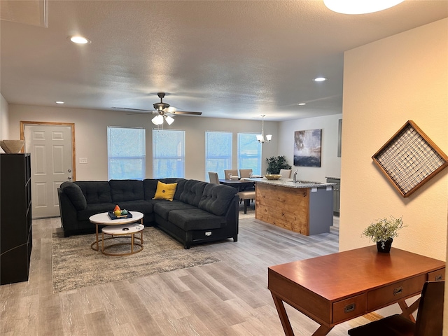 living room featuring ceiling fan, a textured ceiling, and light wood-type flooring