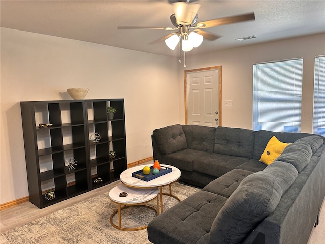 living room with a textured ceiling, ceiling fan, and light hardwood / wood-style flooring