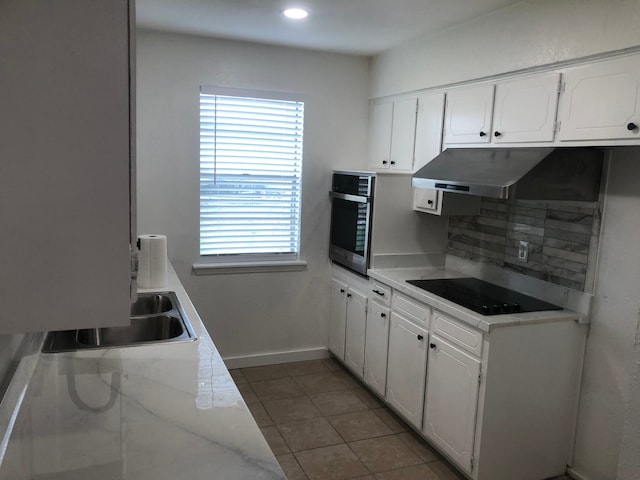 kitchen with oven, black electric stovetop, sink, and white cabinets