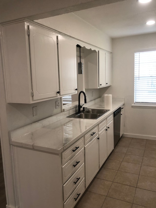 kitchen featuring stainless steel dishwasher, white cabinetry, sink, and tile patterned floors