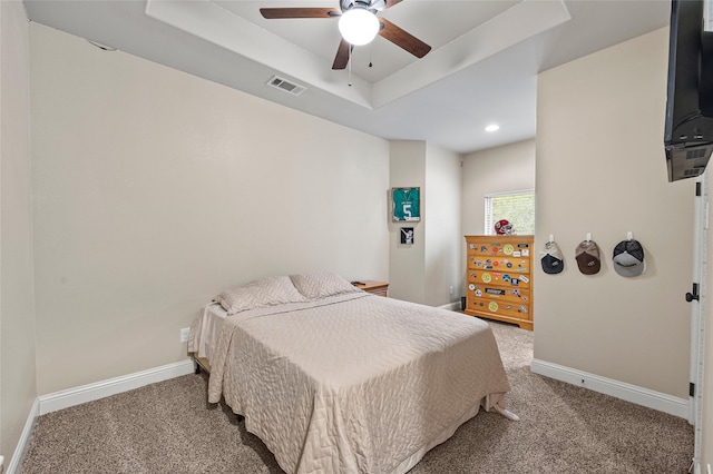 bedroom with carpet flooring, a raised ceiling, visible vents, and baseboards