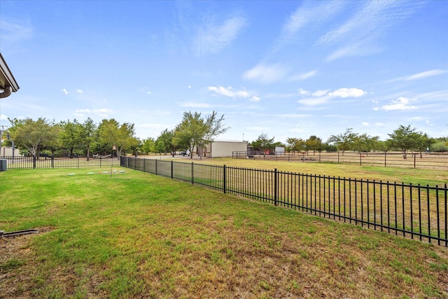 view of yard with an outbuilding, a rural view, and fence