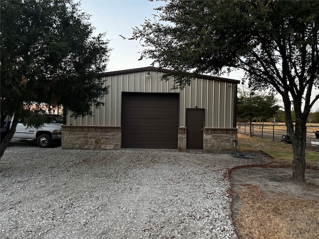 detached garage featuring fence and driveway