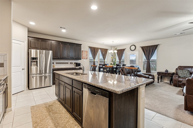 kitchen with an island with sink, sink, dark brown cabinetry, stainless steel appliances, and light carpet