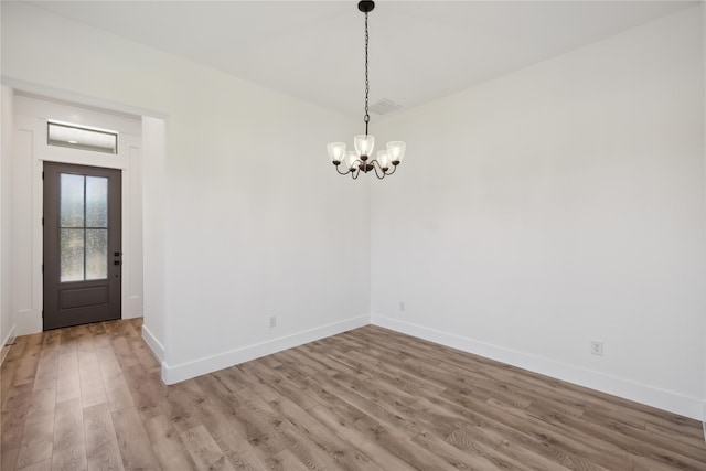 unfurnished room featuring an inviting chandelier and wood-type flooring