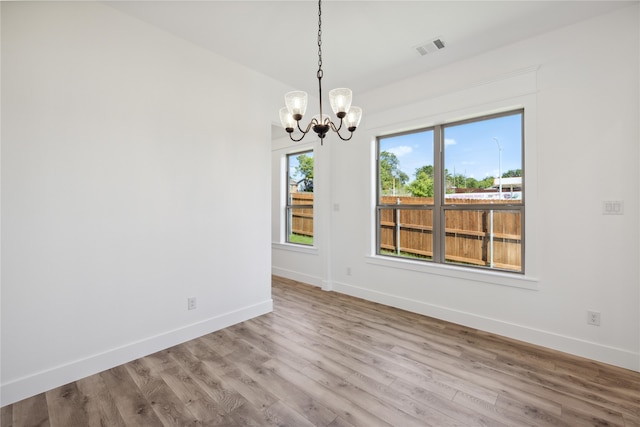 unfurnished room with an inviting chandelier and light hardwood / wood-style flooring