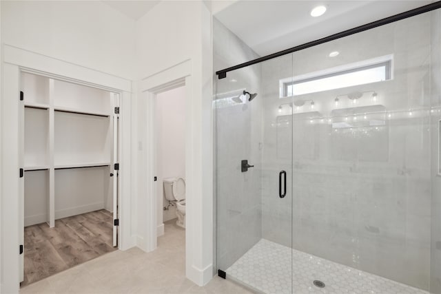 bathroom featuring wood-type flooring, toilet, and a shower with shower door