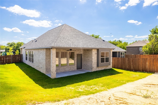 back of property with a yard, ceiling fan, and a patio area