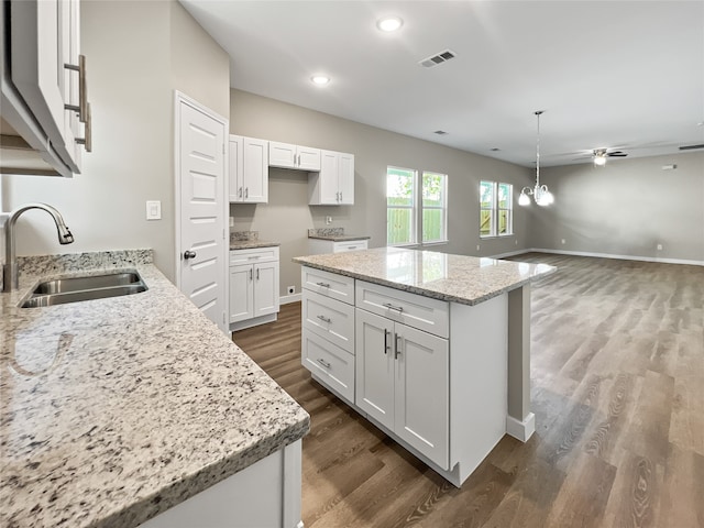 kitchen with a center island, sink, white cabinets, and dark wood-type flooring