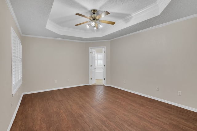 unfurnished room featuring ornamental molding, a raised ceiling, dark hardwood / wood-style flooring, and ceiling fan