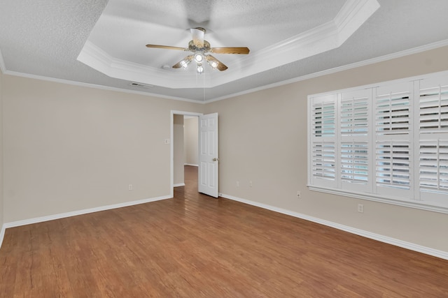 unfurnished room featuring ceiling fan, ornamental molding, a tray ceiling, and hardwood / wood-style flooring