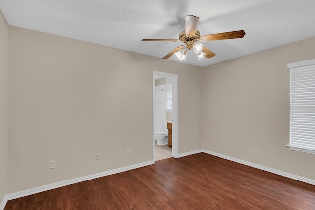 empty room with a textured ceiling, dark wood-type flooring, and ceiling fan