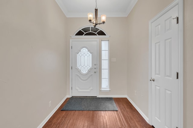 entryway with crown molding, hardwood / wood-style flooring, and a notable chandelier