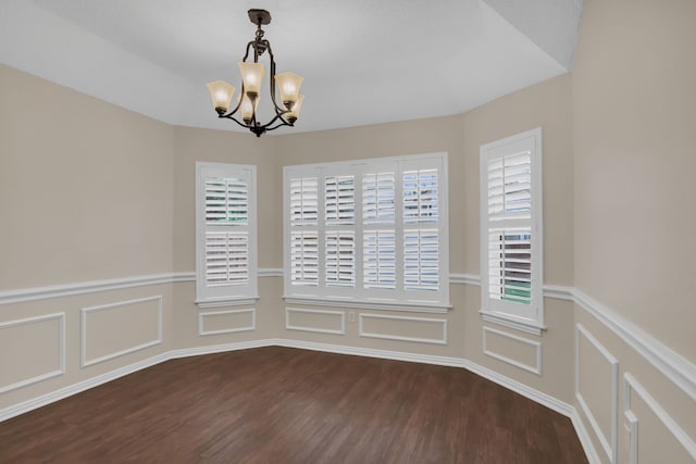 unfurnished dining area with dark wood-type flooring and a chandelier