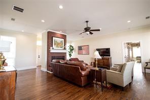 living room with visible vents, a fireplace, crown molding, and wood finished floors