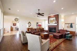 living area featuring dark wood finished floors, crown molding, recessed lighting, and a fireplace