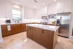 kitchen with brown cabinetry, white microwave, stainless steel fridge with ice dispenser, white cabinetry, and a center island