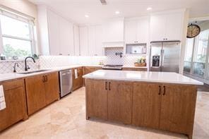 kitchen featuring a sink, stainless steel appliances, a center island, and light countertops