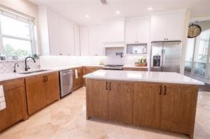 kitchen with a kitchen island, sink, appliances with stainless steel finishes, and tasteful backsplash