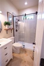 full bathroom featuring toilet, a stall shower, and vanity