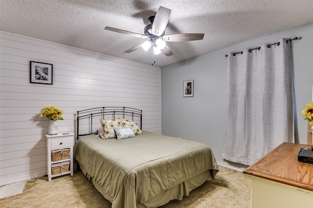 carpeted bedroom with ceiling fan, a textured ceiling, and wood walls