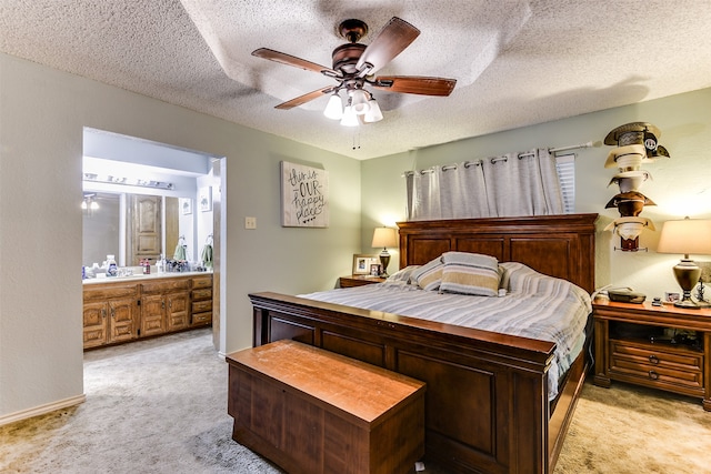 bedroom with ceiling fan, light colored carpet, a textured ceiling, and ensuite bathroom