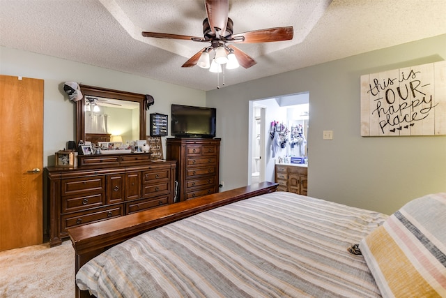 bedroom featuring ceiling fan, a textured ceiling, light carpet, and ensuite bathroom