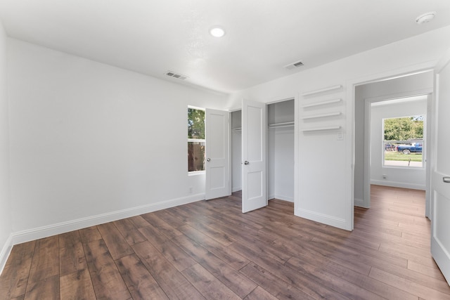 unfurnished bedroom with a closet and dark hardwood / wood-style floors