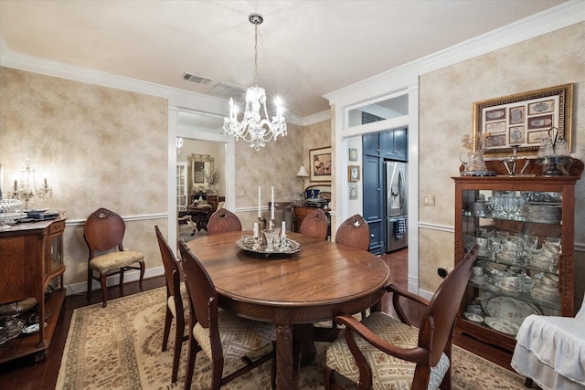 dining space with hardwood / wood-style floors, crown molding, and a notable chandelier