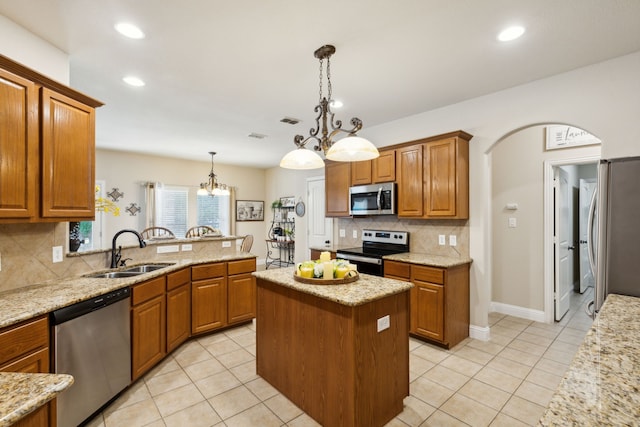 kitchen with a kitchen island, pendant lighting, a notable chandelier, appliances with stainless steel finishes, and sink