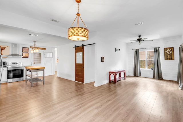 living room with a barn door, ceiling fan, and light hardwood / wood-style flooring