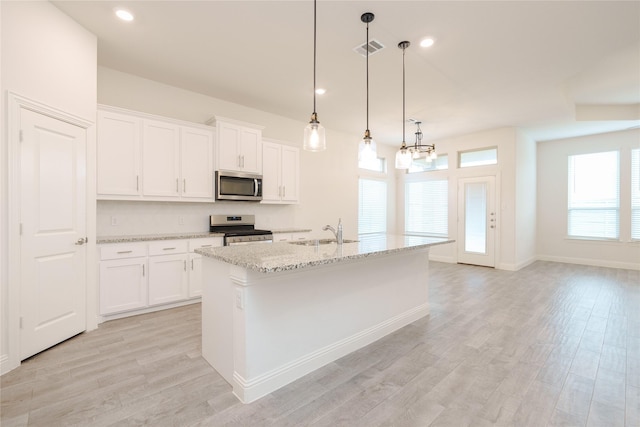 kitchen featuring visible vents, light wood-style flooring, appliances with stainless steel finishes, white cabinetry, and a sink