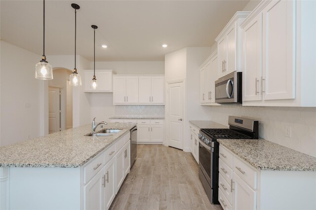 kitchen featuring white cabinets, light wood-type flooring, stainless steel appliances, sink, and pendant lighting