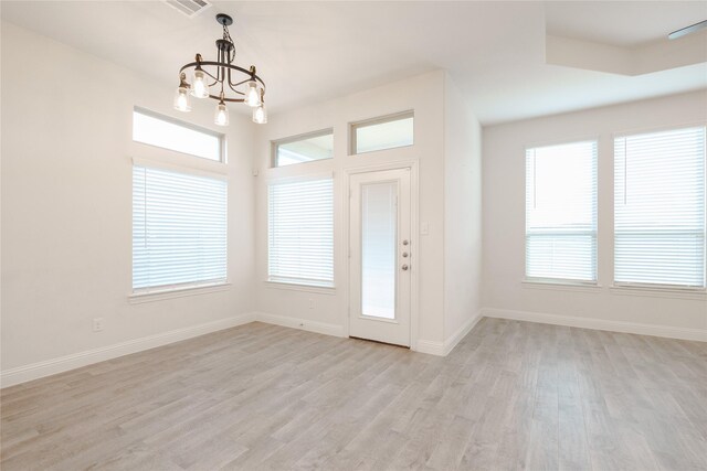 entryway with light hardwood / wood-style floors, a wealth of natural light, and an inviting chandelier