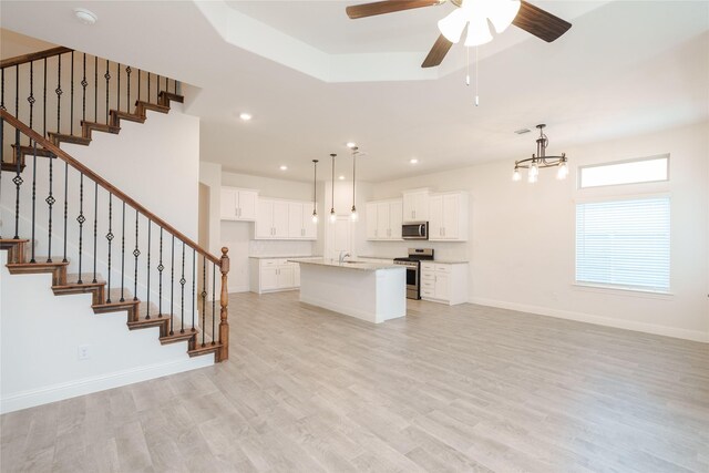 unfurnished living room featuring ceiling fan with notable chandelier, sink, and light hardwood / wood-style floors