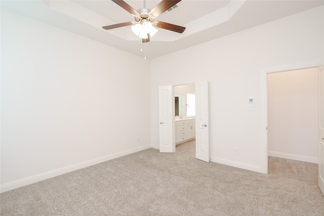 unfurnished bedroom featuring light colored carpet, ceiling fan, and ensuite bath