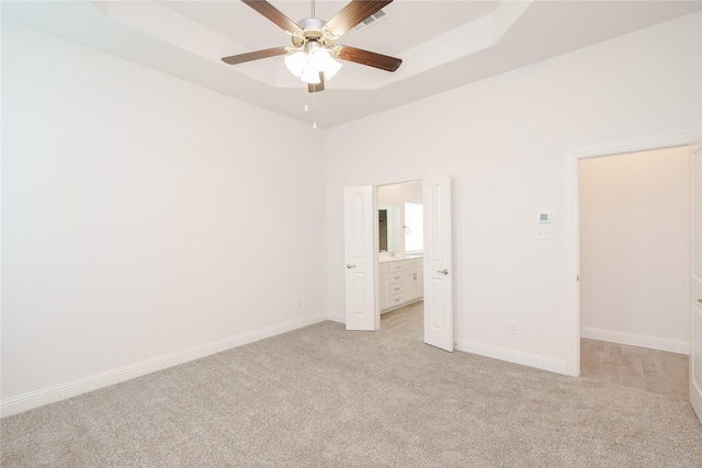 unfurnished bedroom featuring ensuite bath, visible vents, baseboards, and light carpet