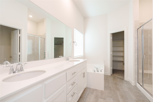 bathroom with plus walk in shower, hardwood / wood-style floors, and vanity