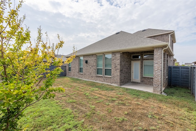 rear view of house with a lawn and a patio