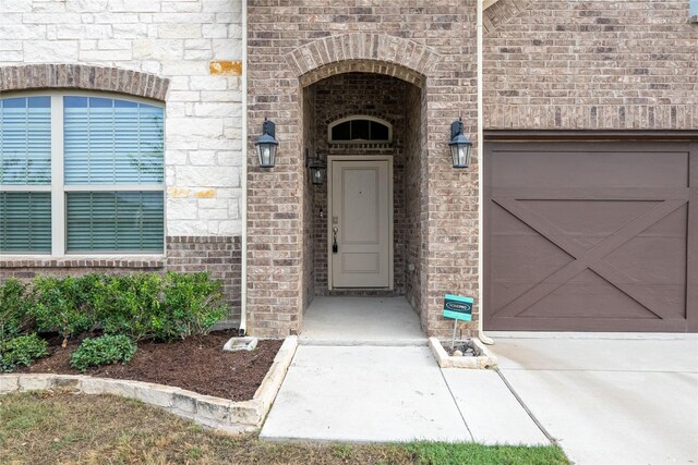 entrance to property with brick siding and an attached garage