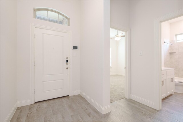 entryway featuring light wood finished floors, a ceiling fan, and baseboards