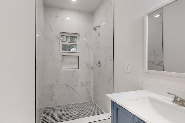 bathroom with tiled shower and vanity