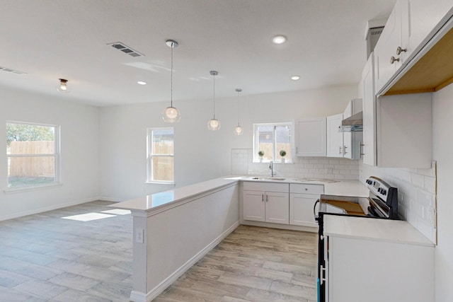 kitchen featuring range hood, white cabinets, sink, and a healthy amount of sunlight