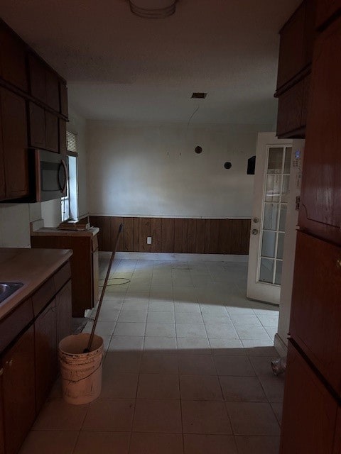 kitchen with wooden walls, light tile patterned flooring, and white refrigerator