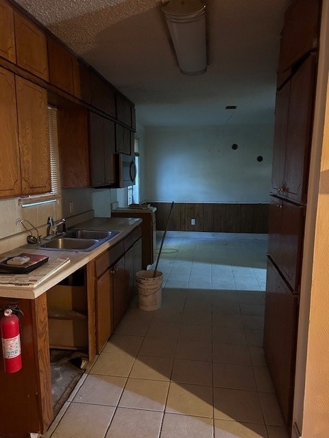 kitchen with light tile patterned flooring, fridge, and sink