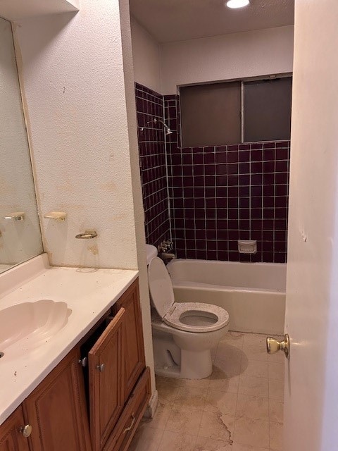 full bathroom featuring vanity, tiled shower / bath, and toilet