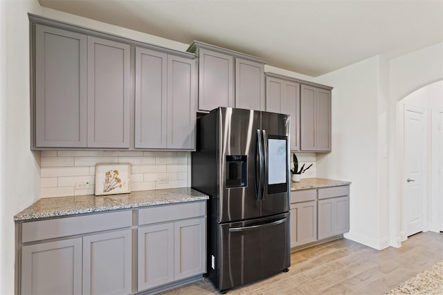 kitchen featuring light stone counters, gray cabinets, and stainless steel refrigerator with ice dispenser