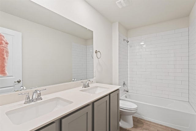 full bathroom featuring vanity, tiled shower / bath, hardwood / wood-style floors, and toilet