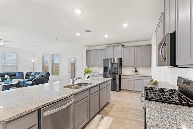 kitchen featuring light hardwood / wood-style flooring, stainless steel appliances, light stone counters, sink, and ceiling fan