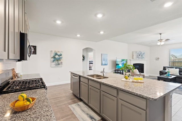 kitchen featuring a kitchen island with sink, light hardwood / wood-style flooring, stainless steel appliances, sink, and ceiling fan